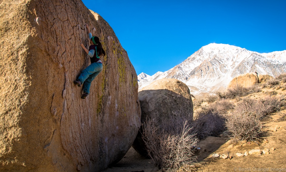 Michelle Forrest bouldering with a snowy mountain behind her