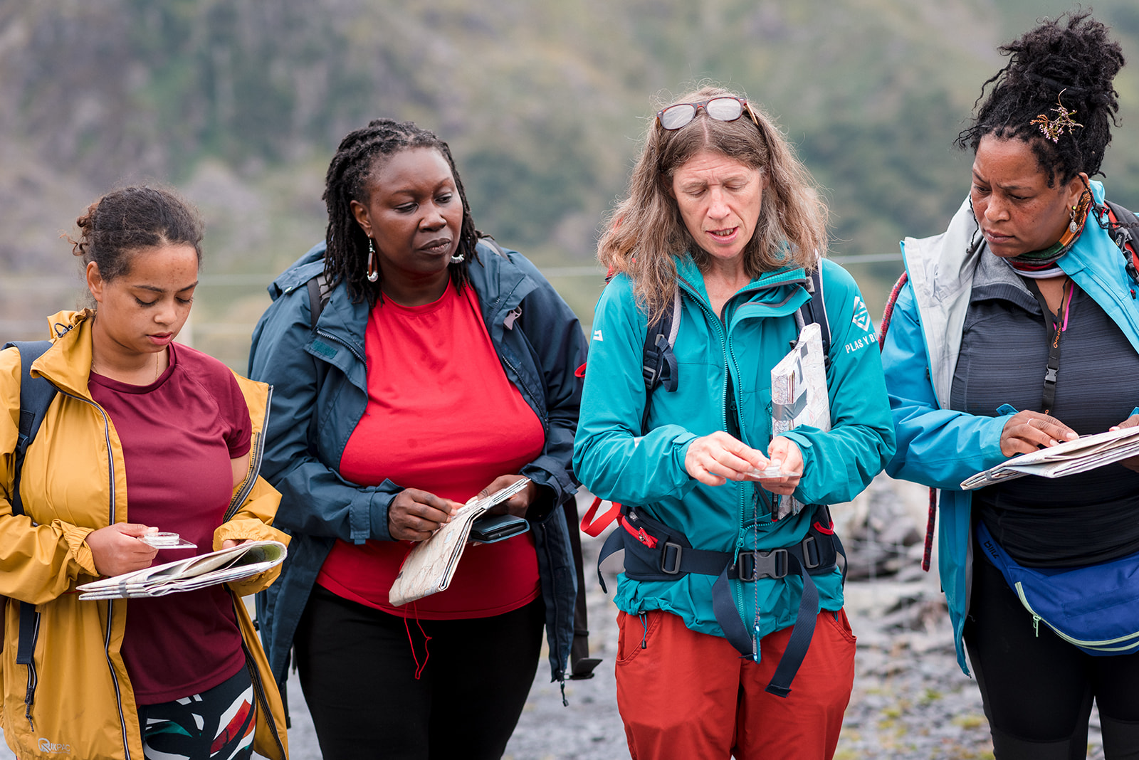 3 black women being given instruction on how to use a map and a compass