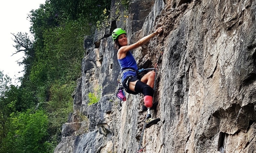 A woman with a prosthetic leg leading a sport climb